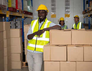 A team of warehouse workers is standing to inspect the finished goods for delivery to customers in the preparation area for delivery within the warehouse.