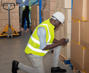 An African American male warehouse worker scanned the barcode, inspecting the quantity of goods stored in the warehouse for inventory.