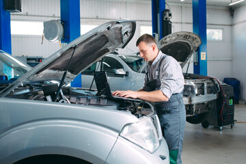 car mechanic using a computer laptop to diagnosing and checking up on car engines parts for fixing...