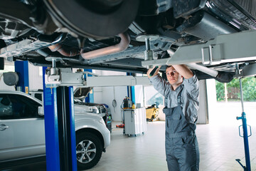 Portrait of a mechanic repairing a lifted car.