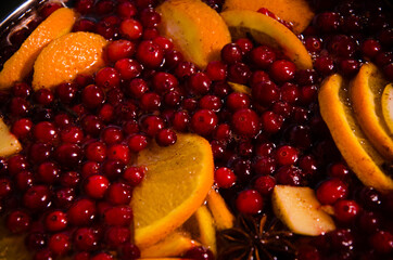 metal pot on the stove. Oranges and cranberries in mulled wine