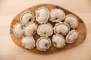 Rye flour dumplings. Russian dumplings on a wooden background tinted photo