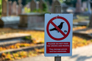 a sign in a cemetery stating do not feed the crows and rooks as they cause damage to graves