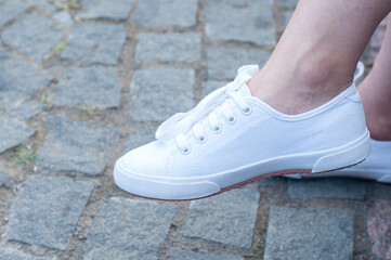 Legs of a young girl in sneakers or moccasins.