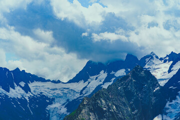 Beautiful mountain landscape in summertime. Mighty mountains with snow in cloudy weather.