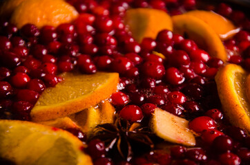 metal pot on the stove. Oranges and cranberries in mulled wine