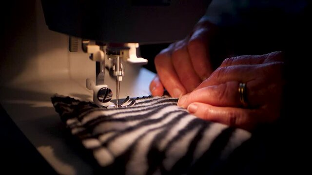 slow motion of a married woman sewing on zebra fabric.