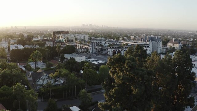 Aerial drone shot in West Hollywood looking out toward the tall skyscraper of downtown LA at sunset