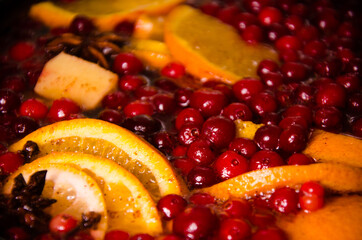 metal pot on the stove. Oranges and cranberries in mulled wine