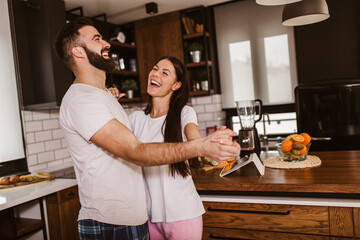 Joyful couple have fun dancing in the kitchen at home in the morning