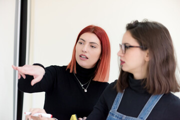 Two young female economy students analyzing company annual financial report balance and prepairing for test. Concept picture of economy, education. market.