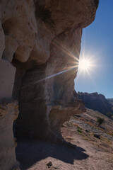 Bright radiant sun over a cave in the mountains