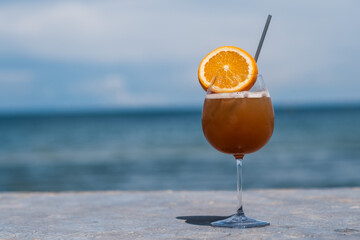 A glass of ice orange juice and sea and blue sky