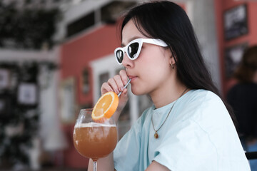 Asian girl drink orange juice in beach cafe