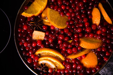 metal pot on the stove. Oranges and cranberries in mulled wine