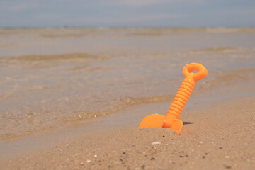 Naklejka premium Orange plastic toy on the beach