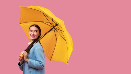 Portrait of cute woman holding umbrella, looking aside © Prostock-studio