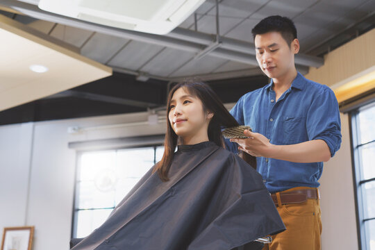 Asian Beautiful Women Happy Hair Treatment In Beauty Salon. Man Hairdresser Provide Service Mind. Hairdressing Equipment Is Clean. End Of Quarantine And Return To Open Salon Hair Work