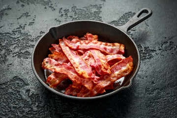 Fried crunchy Streaky Bacon pieces in a cast iron skillet