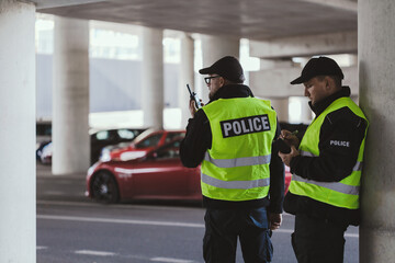 Police officers in black uniforms and yellow vests standing on the parking lot