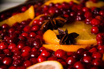 metal pot on the stove. Oranges and cranberries in mulled wine