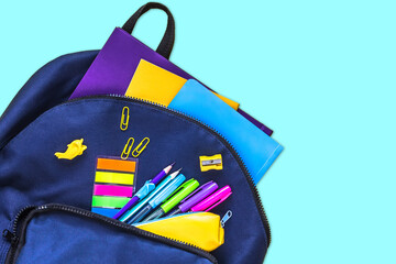 Naklejka premium The concept of going back to school. Blue school bag with school supplies on a blue background. Space for text. The view from the top