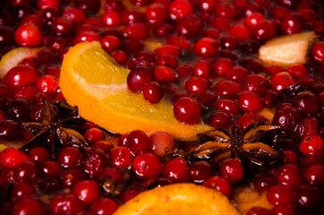 metal pot on the stove. Oranges and cranberries in mulled wine