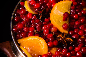 metal pot on the stove. Oranges and cranberries in mulled wine