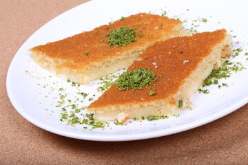 A slice piece of kunafa ramadan Arabic sweet pastries & dessert with creamy cheese & pistachios in the dish