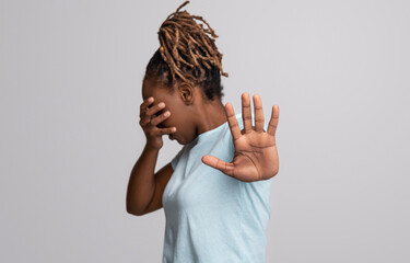 Scared black woman covering face with hand, showing no gesture