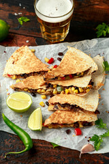 vegetarian mexican black beans tomato cheese and corn quesadilla served with cold beer salsa and yogurt dip sause on dark wooden background. healthy food