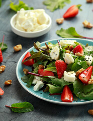 Goats cheese and strawberry summer salad served with nigella and sesame seeds drizzled with runny honey