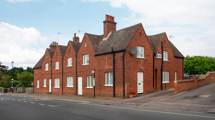 Road with no traffic passing through the quaint residential area lined with beautiful traditional Georgian brick houses and gardens in Bedford Street, Woburn, Bedfordshire, England