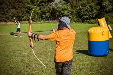 Teenage boy playing archery tag on a meadow
