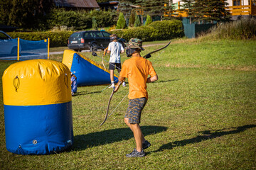 Teenage boy playing archery tag on a meadow