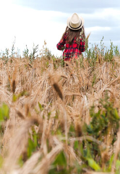 The child is out of focus and goes into the distance across the rye field. Selective, soft focus, vertical image.