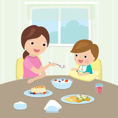 Small caucasian child sits on a highchair. Cartoon Mom feeds the boy healthy food. Breakfast in the kitchen.