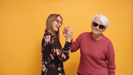 Trendy cool granny and young woman doing high five. Studio shot. High quality photo