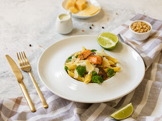 Pasta penne with salmon, broccoli, and pesto sauce on the white-gray background. Flat lay.