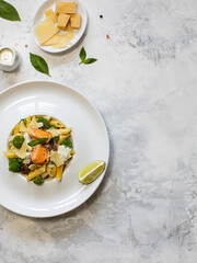 Pasta penne with salmon, broccoli, and pesto sauce on the white-gray background. Flat lay.