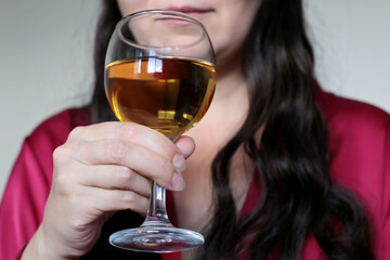 Woman drinks a white wine in a glass. Sensual girl enjoying the alcohol, concept of celebration, relax at home, female alcoholism