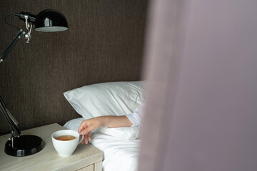 Female hand  reaches for a cup after wake up. View through the curtain window.