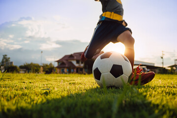 Boy kicking a ball while playing street soccer football on the green grass field for exercise....