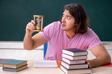 Young male student in the classroom at time management concept