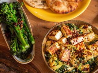 Saag Paneer served in a bowl with side of naan and tender stem broccoli 