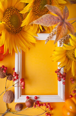 Greeting autumn card. Composition with wooden white frame with autumn leaves, pumpkin, sunflower and berries. Cozy autumn mood concept.