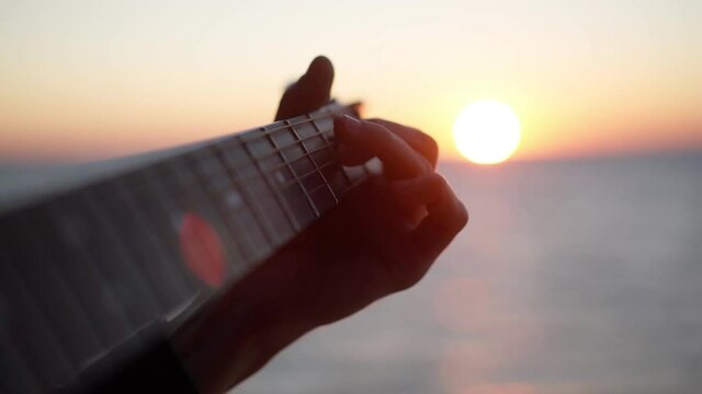 Playing guitar at sunrise by the sea