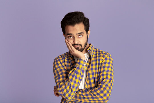 Handsome Indian man feeling bored or tired on lilac background