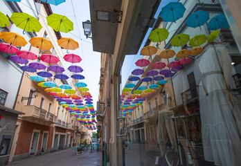 Iglesias, Italy: Colorful umbrellas hanging over a street in old Iglesias city in a sunny day

