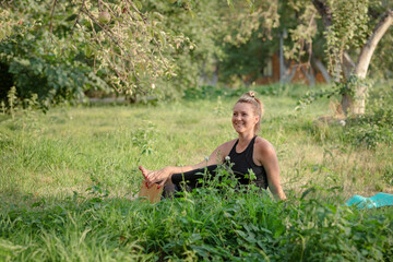 Naklejka na ściany i meble The girl does physical exercises in the fresh air, in a picturesque place, against the background of an Apple orchard. the concept of a healthy lifestyle. Selective focus.